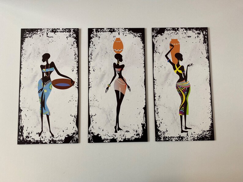 May include: Three black and white silhouette paintings of women in colorful clothing carrying various items on their heads. The paintings have a distressed white background with black borders.