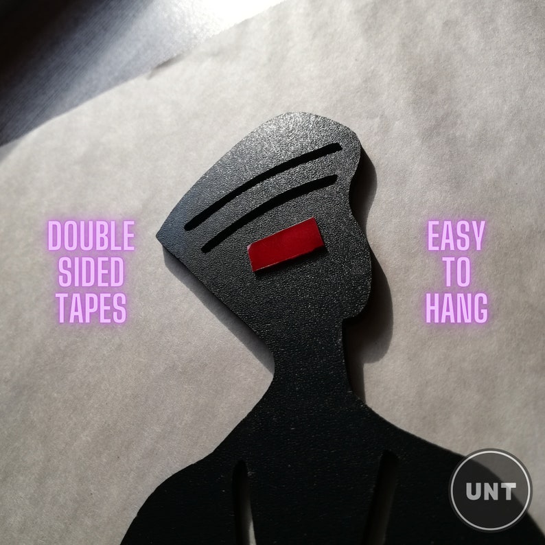 May include: Black silhouette of a person with a red rectangle on the head. The text "DOUBLE SIDED TAPES" is on the left and "EASY TO HANG" is on the right. The text "UNT" is in the bottom right corner.