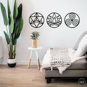 May include: Three black metal wall decor pieces in the shape of circles. The circles feature geometric designs, including a flower, a star, and a spiral. The decor is hanging on a white wall in a living room setting.