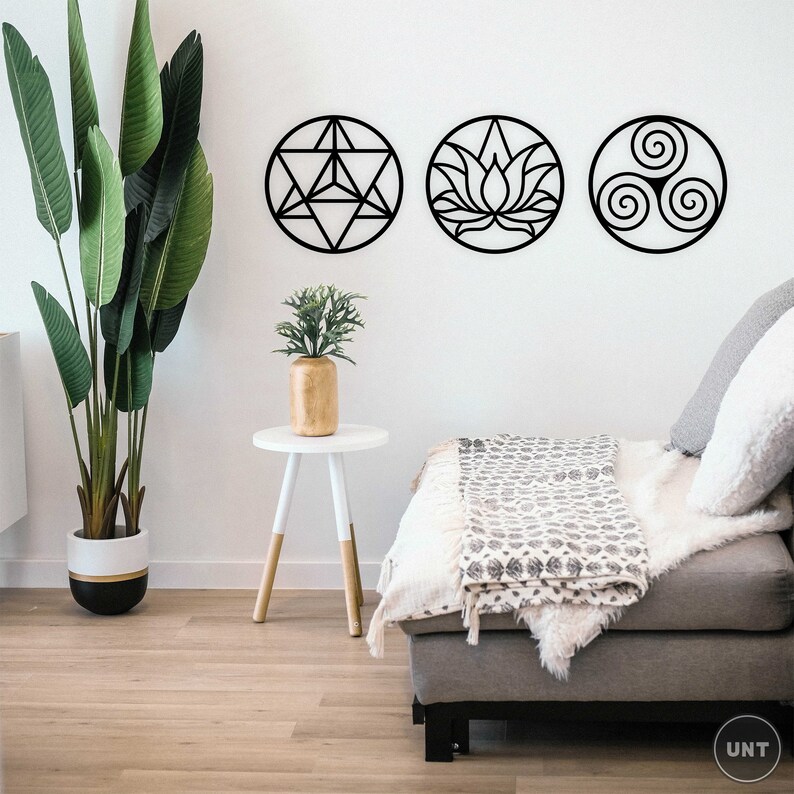 May include: Three black metal wall decor pieces in the shape of circles. The circles feature geometric designs, including a flower, a star, and a spiral. The decor is hanging on a white wall in a living room setting.