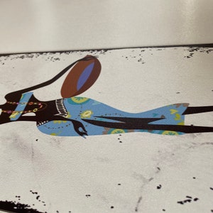 May include: A stylized illustration of a woman in a blue and brown patterned dress carrying a large pot on her head. The background is a white canvas with black speckles.