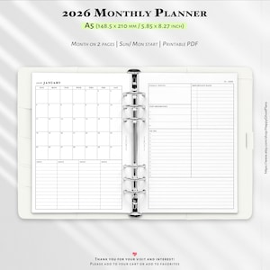 May include: A white A5 2026 monthly planner with a silver binder. The planner is open to a January calendar spread, with space for goals, priorities, and to-do lists. The planner measures 5.85 x 8.27 inches.