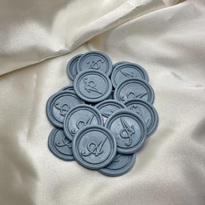 May include: A pile of 15 blue wax seals with a decorative script letter "A" design.