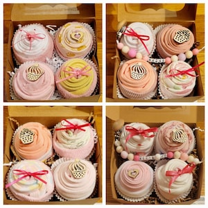 May include: Four boxes of baby gifts, each containing six cupcake-shaped baby socks in various pastel colors. Each cupcake is decorated with a wooden cupcake topper and tied with a pink ribbon. Some boxes include a pacifier clip and a beaded bracelet.