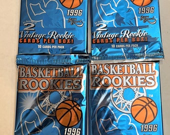 May include: Four unopened packs of 1996 Basketball Rookies trading cards. Each pack is blue with a basketball graphic and the text "Basketball Rookies" and "Vintage Rookie Cards Per Box!" The packs are from The Score Board.