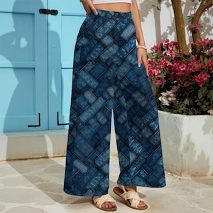 May include: Wide-leg denim-look pants with a woven pattern in shades of blue. The pants have a high waist and a relaxed fit. The model is wearing sandals. The background includes a blue door and a flower pot with pink flowers.