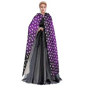 May include: A purple hooded cape with white stars and crescent moons printed on it. The cape is worn over a black tulle dress.