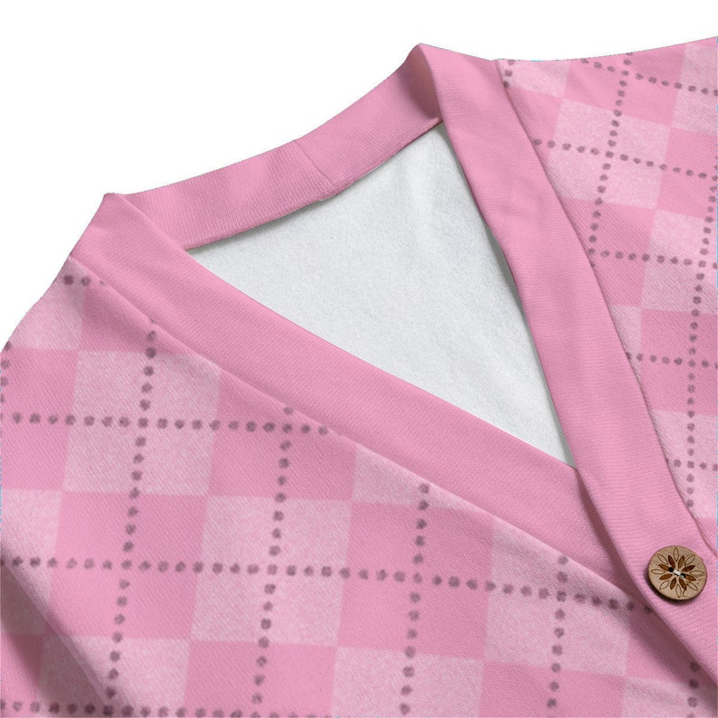 Puede incluir: Primer plano de una chaqueta de punto rosa con un patr&oacute;n de cuadros y un solo bot&oacute;n de madera. La chaqueta tiene cuello en V y est&aacute; hecha de un tejido suave y el&aacute;stico.
