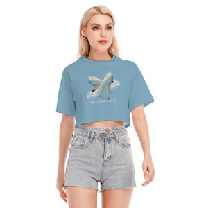 May include: A light blue cropped t-shirt with a graphic of two blue high heels and the text "Head over heels".