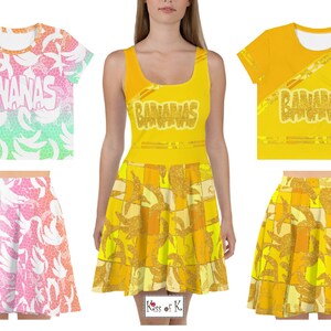 May include: A set of clothing featuring a banana pattern. The set includes a yellow dress with a "Bananas" graphic, a yellow crop top with a "Bananas" graphic, a yellow skirt with a banana pattern, a pink and green skirt with a banana pattern, and a white crop top with a banana pattern.