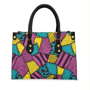 May include: A patterned handbag featuring a patchwork design in teal, yellow, purple, and black. The bag has black handles and gold-coloured hardware. The design includes stitched shapes and swirls, creating a unique accessory. The bag is approximately 30 cm wide.