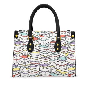 May include: A rectangular tote bag with a black handle and a colorful book pattern. The bag features a white background with stacks of books in various colors, including red, yellow, purple, and blue. The handles are black.
