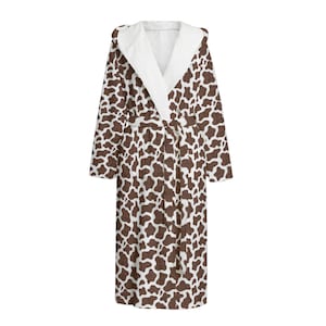 May include: A long white robe with a brown cow print pattern. The robe has a hood and a tie belt.