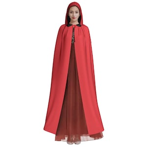 May include: A red hooded cape with a black trim around the neckline and hood. The cape is long and flowing, and the hood is pointed.