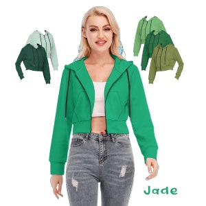 May include: A cropped green zip-up hoodie with a hood and pockets. The model is wearing the hoodie with jeans and has the word "Jade" written below the image.