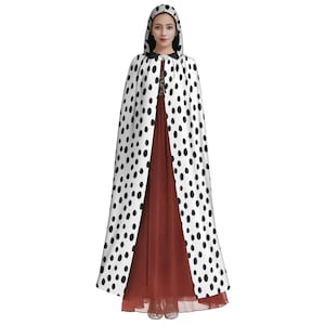 May include: A white hooded cape with black polka dots. The cape is long and flowing, and the hood is lined with black fabric.