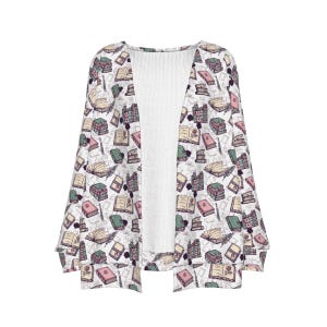 May include: A white open-front cardigan with a repeating pattern of books, quills, and inkwells in shades of pink, green, and beige. The cardigan has long sleeves and a white ribbed panel down the center.