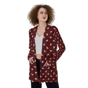 May include: A long-sleeved cardigan with a burgundy background and a white pattern of small, abstract shapes. The cardigan has two pockets and a V-neck.