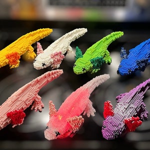 May include: A collection of ten axolotl figurines made of colorful plastic building blocks. The axolotls are in various poses and colors, including yellow, white, green, blue, pink, and purple.