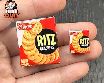 Può includere: Due scatole in miniatura di Ritz Crackers. Le scatole sono rosse e bianche, con il logo Oxford. Il marchio è in bianco su un cerchio nero, con una pila di cracker. Una scatola è più grande dell'altra, entrambe sono in miniatura.