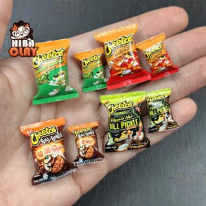 以下が含まれることがあります： 様々なフレーバーのミニチュアCheetosスナックバッグ。Crunchy、Jalapeño、Dill Pickleなど。バッグはオレンジ、緑、赤で、詳細なグラフィックとテキストが施されています。手作りの食品ミニチュアのコレクション。
