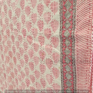 May include: White cotton fabric with a pink and black floral print. The fabric has a border with a geometric pattern.