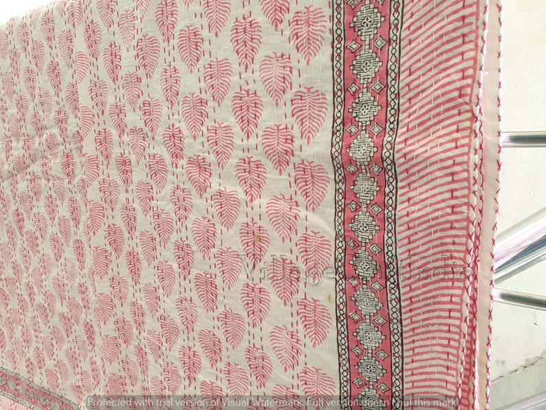 May include: White cotton fabric with a pink and black floral print. The fabric has a border with a geometric pattern.