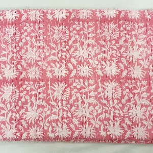 K&ouml;nnte beinhalten: Eine rosa und wei&szlig; gemusterte Steppdecke. Die Steppdecke weist ein sich wiederholendes Design aus gro&szlig;en Blumen und Bl&auml;ttern auf, die mit einem kontrastierenden Faden zusammengen&auml;ht sind. Die Gesamt&auml;sthetik ist weich und feminin, geeignet f&uuml;r Bettw&auml;sche oder dekorative Zwecke.