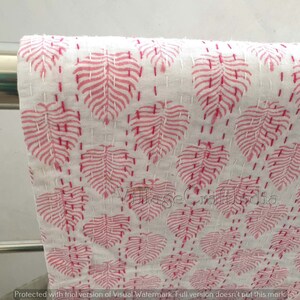 May include: White cotton fabric with a pink leaf pattern. The fabric is quilted with small stitches.