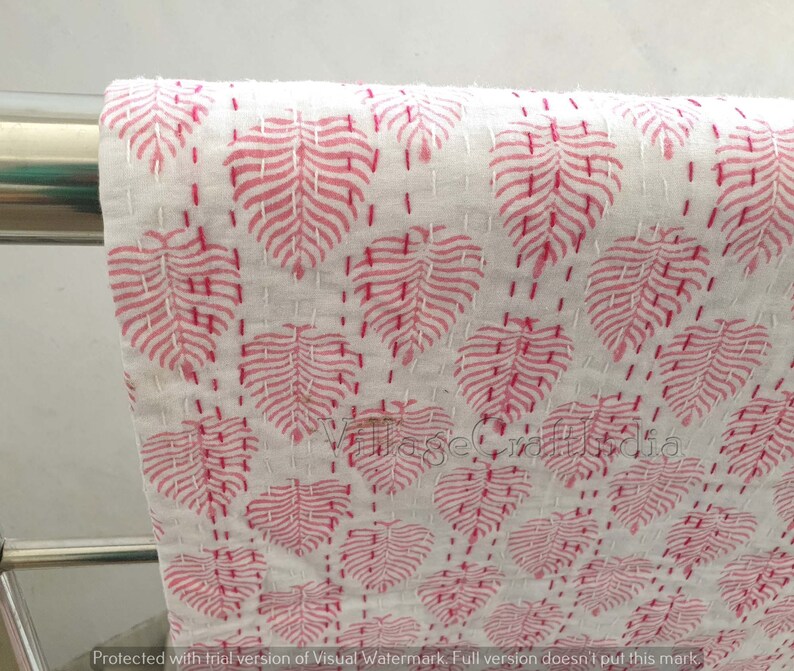 May include: White cotton fabric with a pink leaf pattern. The fabric is quilted with small stitches.