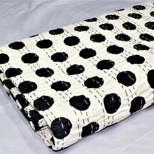 May include: White cotton quilt with a black polka dot pattern. The quilt is folded in half and has a hand-stitched design.