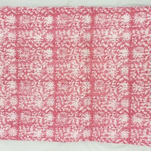 K&ouml;nnte beinhalten: Ein Textil mit rosa und wei&szlig;em Blumenmuster. Das Design zeigt sich wiederholende wei&szlig;e Blumen- und Blattmotive auf rosa Hintergrund. Der Stoff scheint mit sichtbaren N&auml;hten im gesamten Design gesteppt zu sein.