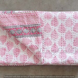 May include: A pink and white kantha quilt with a leaf pattern. The quilt is folded in half and has a decorative border.