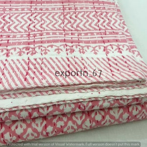 May include: Pink and white kantha quilt with a floral pattern. The quilt is folded in thirds and has a white border.