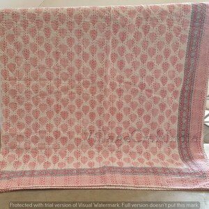 May include: A white cotton quilt with a pink floral pattern. The quilt has a gray and pink border.