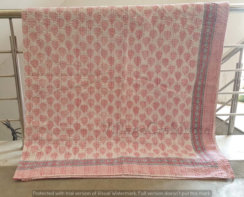 May include: A white cotton quilt with a pink floral pattern. The quilt has a gray and pink border.