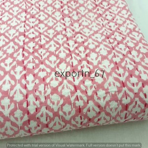May include: Pink cotton fabric with a white floral pattern. The fabric is quilted with a small stitch. The fabric is folded in half and the text "exportn_67" is visible in the center of the image.