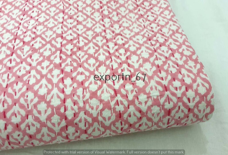 May include: Pink cotton fabric with a white floral pattern. The fabric is quilted with a small stitch. The fabric is folded in half and the text "exportn_67" is visible in the center of the image.