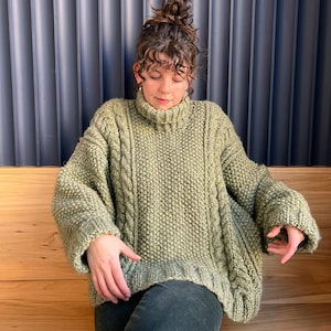 Könnte beinhalten: Ein grüner Strickpullover mit Rollkragen. Der Pullover ist Oversize und hat eine lockere Passform.