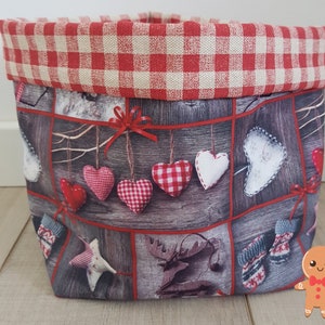 Può includere: Un cesto di stoffa gingham rosso e bianco con una stampa boschiva con cuori, guanti e una renna. La stampa è un collage di diverse immagini.