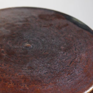 Peut inclure: Gros plan sur le dessus d'un pot en céramique brun foncé avec une surface texturée.