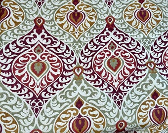 May include: Close-up of a fabric with a repeating pattern. The design features ornate, teardrop-shaped motifs in shades of red, burgundy, gold, and sage green, set against a white background. The fabric has a detailed, symmetrical design.