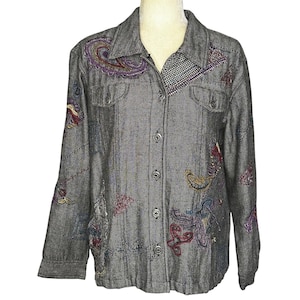 May include: Gray button-down jacket with colorful embroidered paisley and floral designs. The jacket features a small checkered pattern on the collar and pockets. The long-sleeved jacket has silver buttons and two chest pockets.