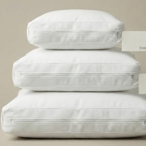 Può includere: Tre cuscini quadrati bianchi impilati, ciascuno con una cerniera. I cuscini sono etichettati "Small", "Medium" e "Large" su piccole schede. Lo sfondo è di colore beige neutro.