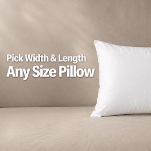 May include: A rectangular white pillow with a smooth surface. The text on the left side reads Pick Width & Length Any Size Pillow. The pillow features a small dark blue tag on the bottom right corner and has a clean, simple design.