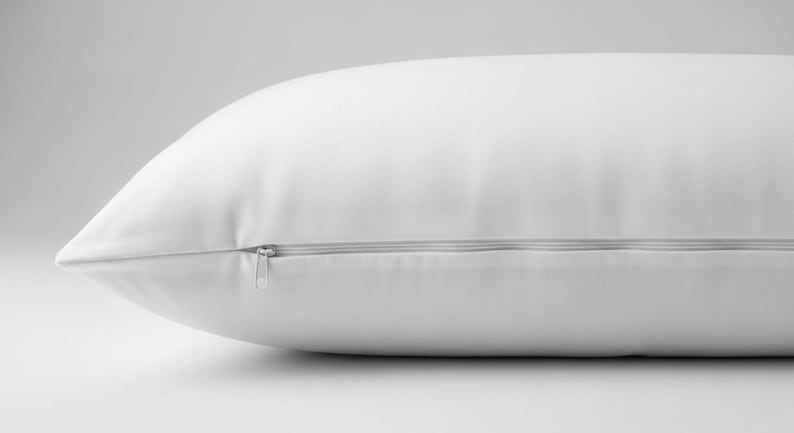 May include: A white pillow with a zipper closure, shown in a side view. The pillow has a smooth, clean appearance, suggesting a focus on comfort and bedding. The zipper is silver.