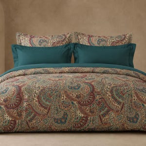 May include: A bedding set featuring a duvet cover and two pillowcases with a complex paisley pattern in shades of deep red, teal, and cream. The set includes two solid teal rectangular pillow shams layered in front of the patterned pillows.