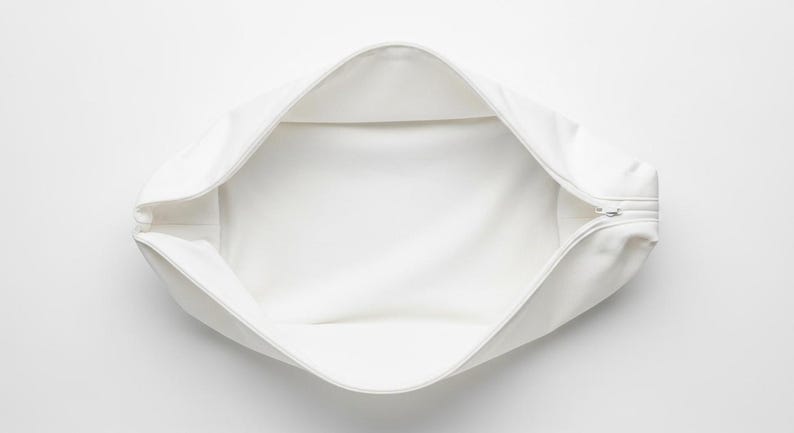 May include: A white, open, rectangular pouch with a zipper closure. The interior is also white, and the pouch is empty. The pouch is made of a soft, smooth material.