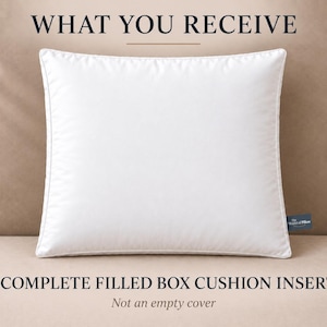 Op de afbeelding: Een vierkant wit kusseninzetstuk met een box-constructie. De tekst WHAT YOU RECEIVE staat bovenaan en 1 COMPLETE FILLED BOX CUSHION INSERT Not an empty cover staat onderaan. Een klein donkerblauw label vermeldt The World of Pillow.