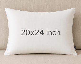 May include: A rectangular off-white throw pillow featuring the text 20x24 inch printed in dark gray on the front. The pillow has a smooth, solid-colored fabric cover and a small dark tag visible on the right side edge of the pillow casing.